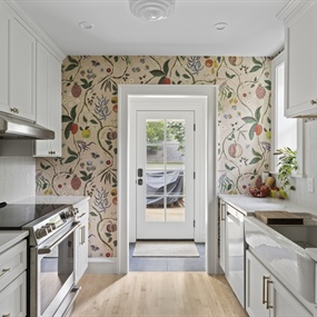 Remodeled Minneapolis kitchen featuring white cabinets, floral wallpaper, wood flooring, and stainless steel appliances.