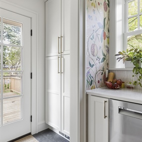 Renovated kitchen entryway with white storage cabinets, natural light, and dark tile flooring in Minneapolis.