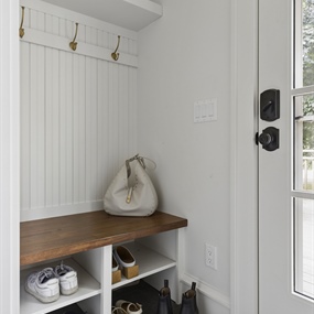 Custom mudroom storage with white built-in cabinets, open shelving, and a wooden bench in a King Field home.