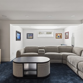 Finished basement living room with a large sectional sofa, built-in shelving, and blue carpet in a Minneapolis home.