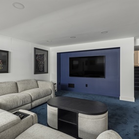 Finished basement entertainment area featuring a large TV, blue accent wall, and sectional sofa in Lynnhurst.