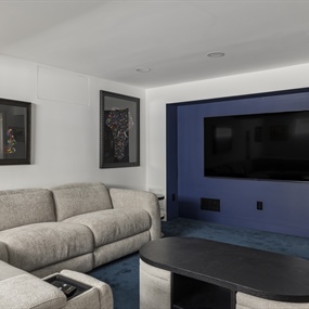 Close-up of a basement home theater with a wall-mounted TV and blue accent wall in a Minneapolis remodel.