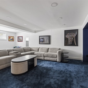 Spacious basement remodel with recessed lighting, blue carpeting, and a custom home theater setup.