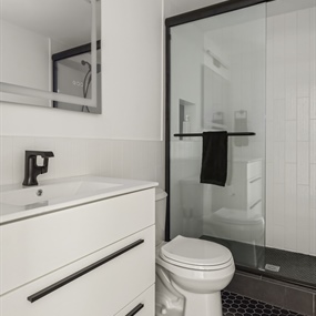 Basement bathroom renovation with a glass-enclosed shower, white vanity, and patterned tile flooring in Minneapolis.